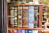 A bookshelf showcasing a collection of classic literature with ornate book covers. Featured titles include works by Fitzgerald, Lovecraft, Doyle, Shakespeare, Carroll, and Stoker. The covers are elaborately designed, with some featuring illustrations like a keyhole and an image of Alice from Alice's Adventures in Wonderland.