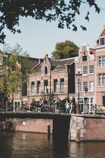 Smiling travelers taking a selfie in front of Amsterdam’s iconic canals and bridges.