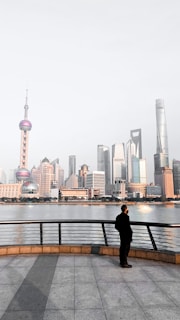 man in black jacket sitting on bench near body of water during daytime