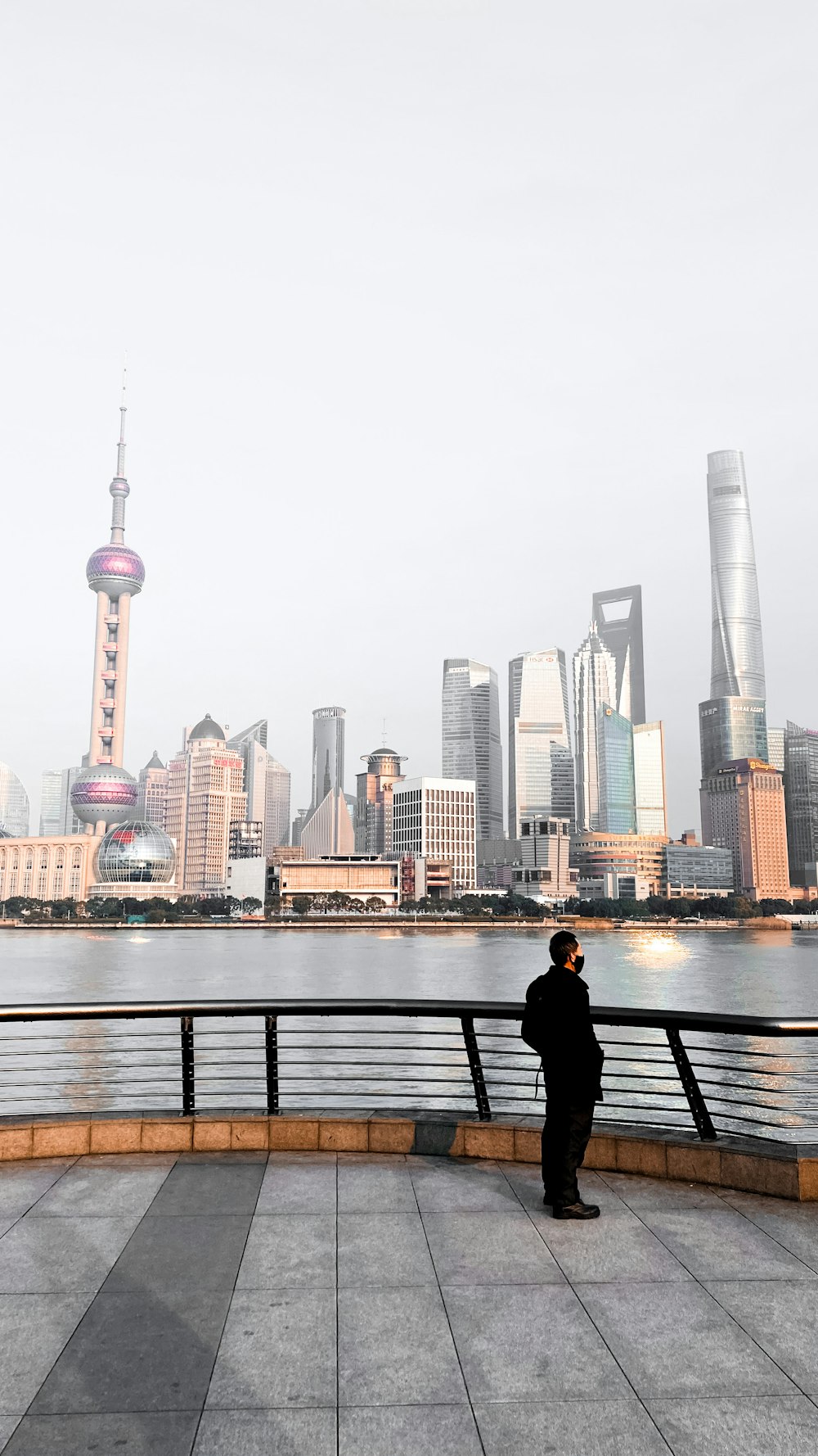 man in black jacket sitting on bench near body of water during daytime