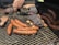 A barbecue grill is loaded with an assortment of meats, including sausages, ribs with charred edges, and a larger piece of meat that appears to have seasoning or a crust. The meats are positioned on the grates, demonstrating a well-cooked, smoky appearance.