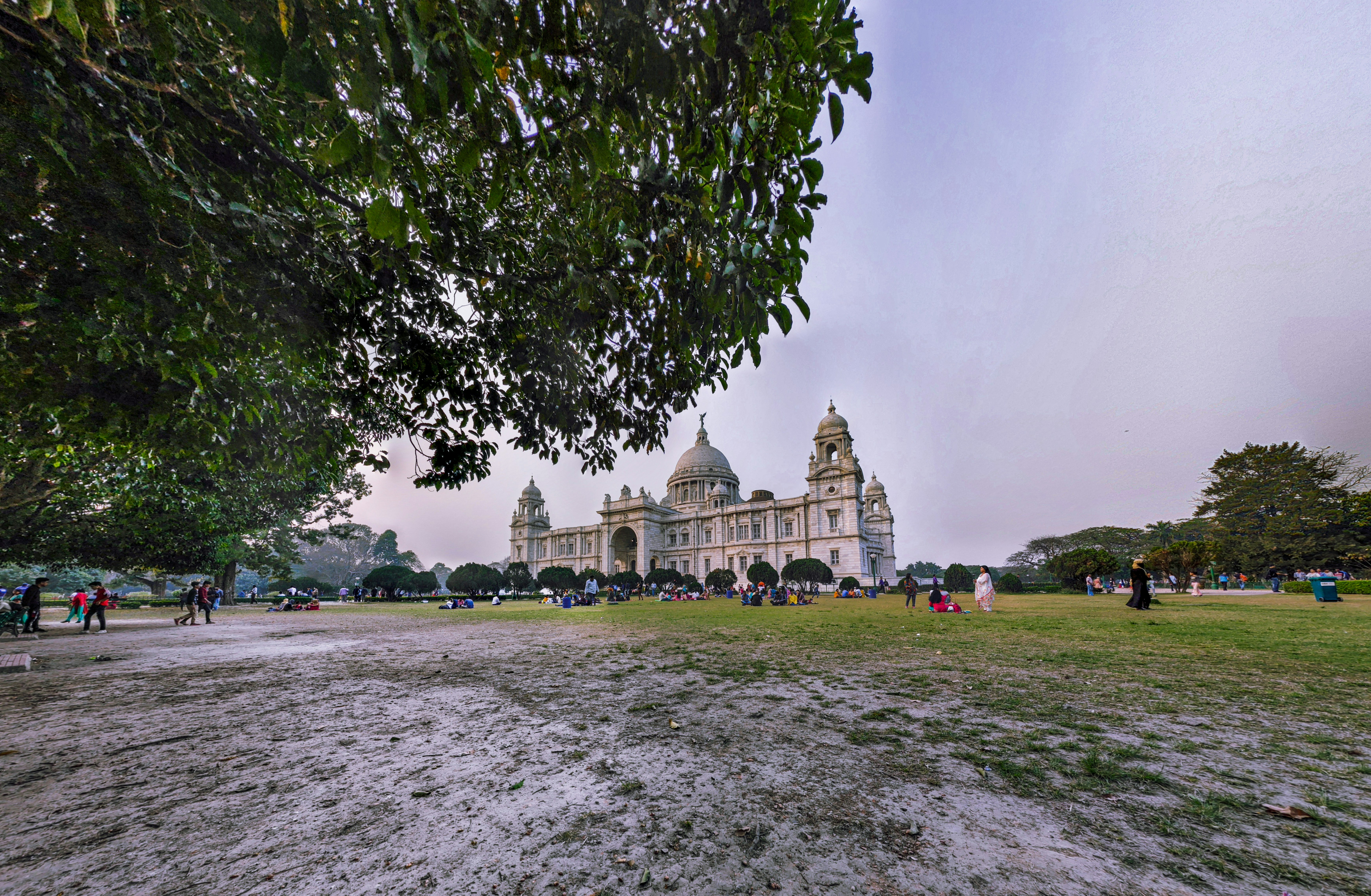 Edificio de hormigón marrón cerca de árboles verdes bajo el cielo blanco durante el día