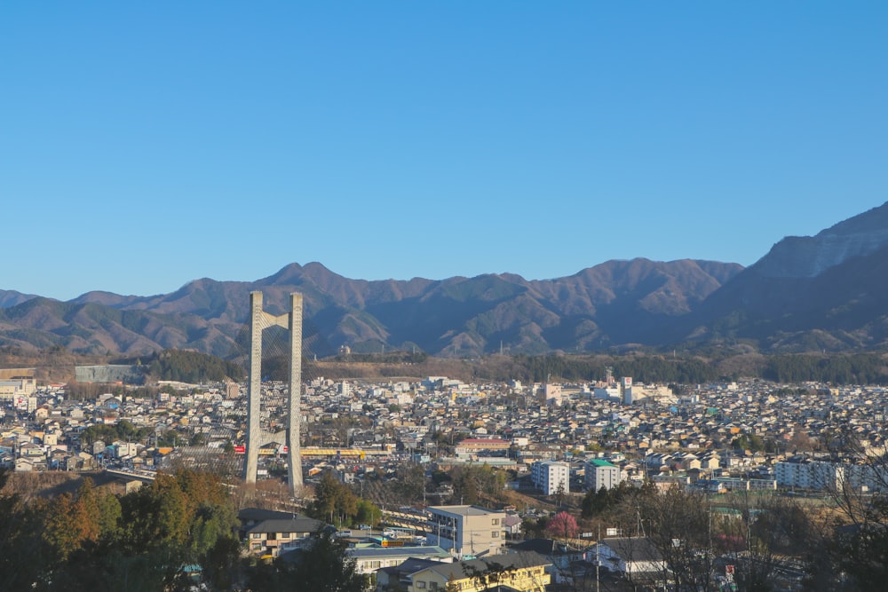 昼間の青空の下、山の近くに高層ビルが立ち並ぶ街