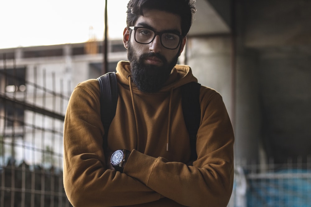 Hombre con sudadera con capucha marrón y negro con anteojos montados negros