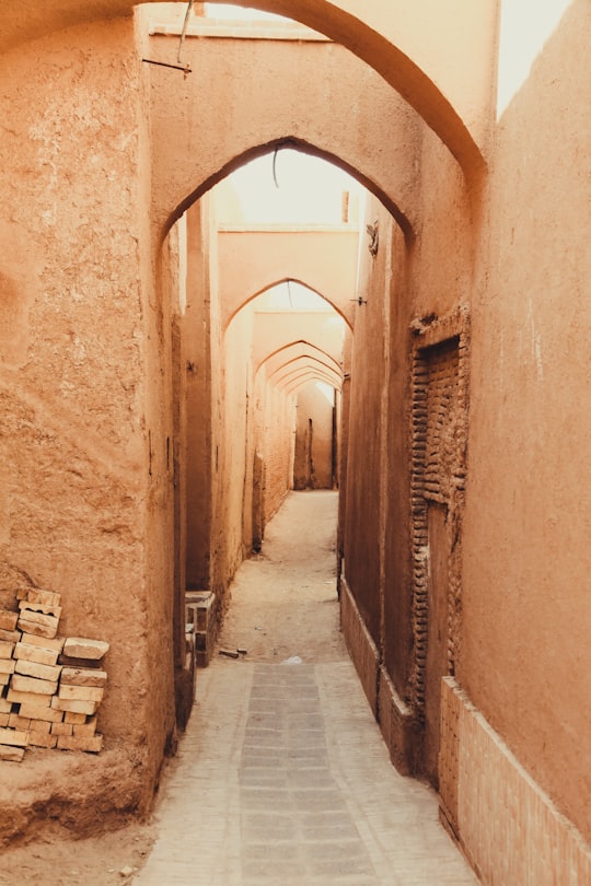 brown wooden benches on brown concrete brick wall in Yazd Iran