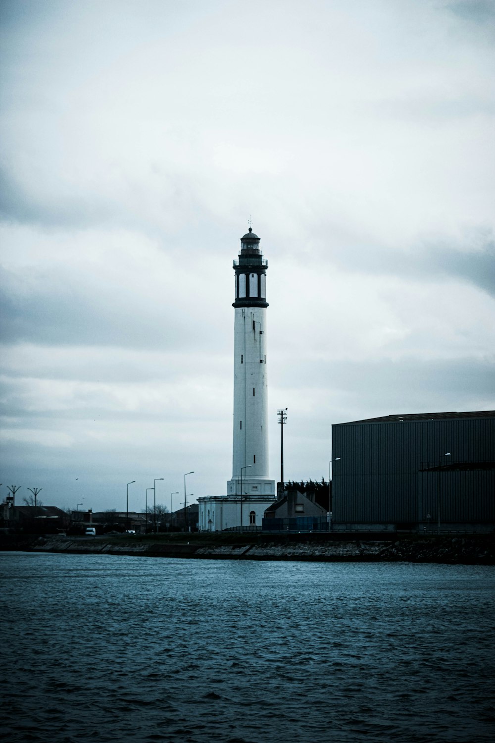 Weißer Leuchtturm in der Nähe des Gewässers tagsüber