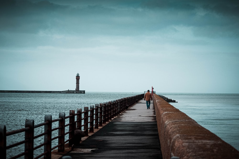 person walking on wooden dock during daytime