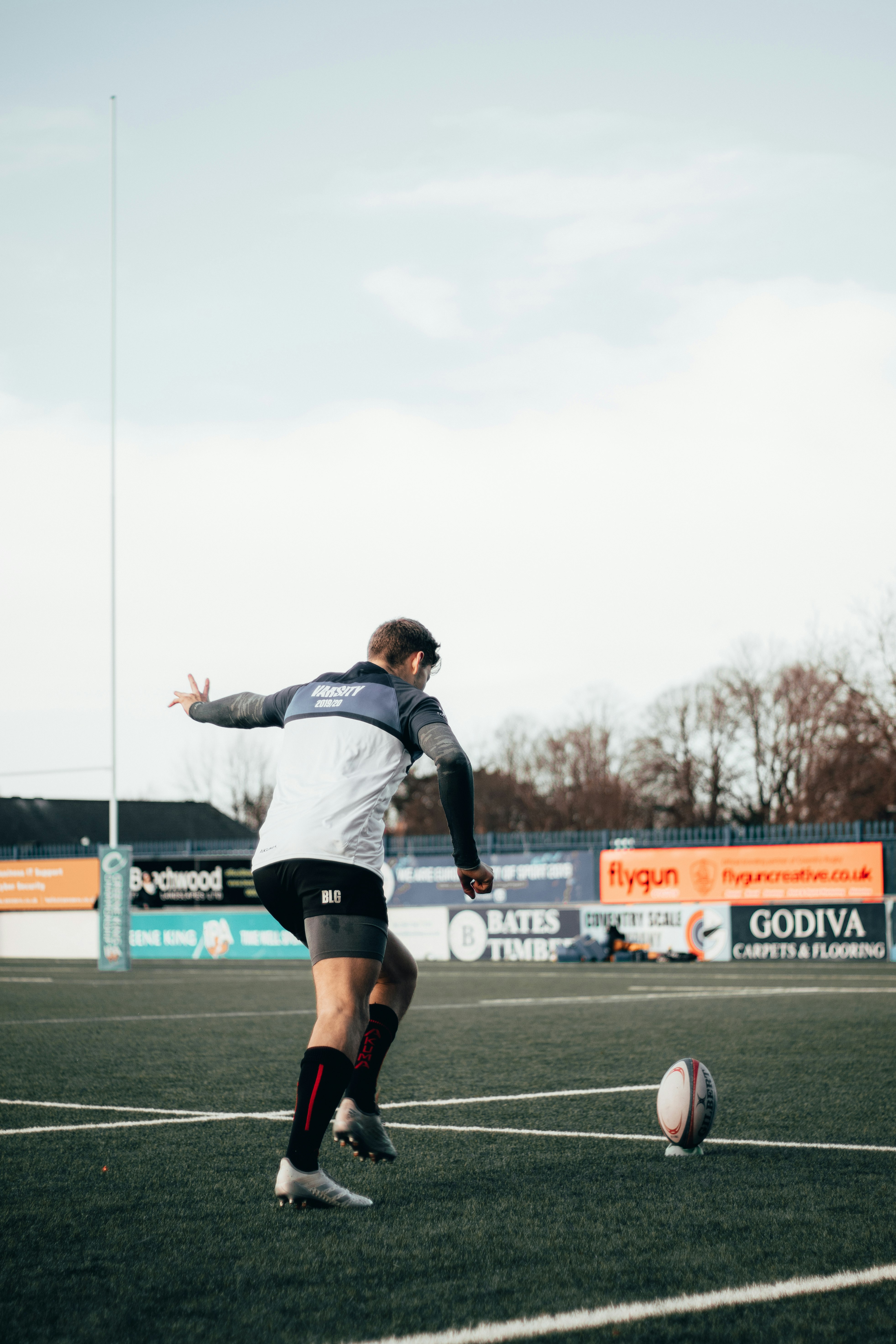 man in gray shirt and black shorts playing soccer during daytime