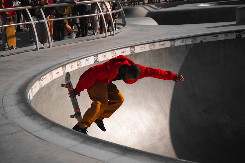 man in red jacket and brown pants jumping on white and black round tunnel