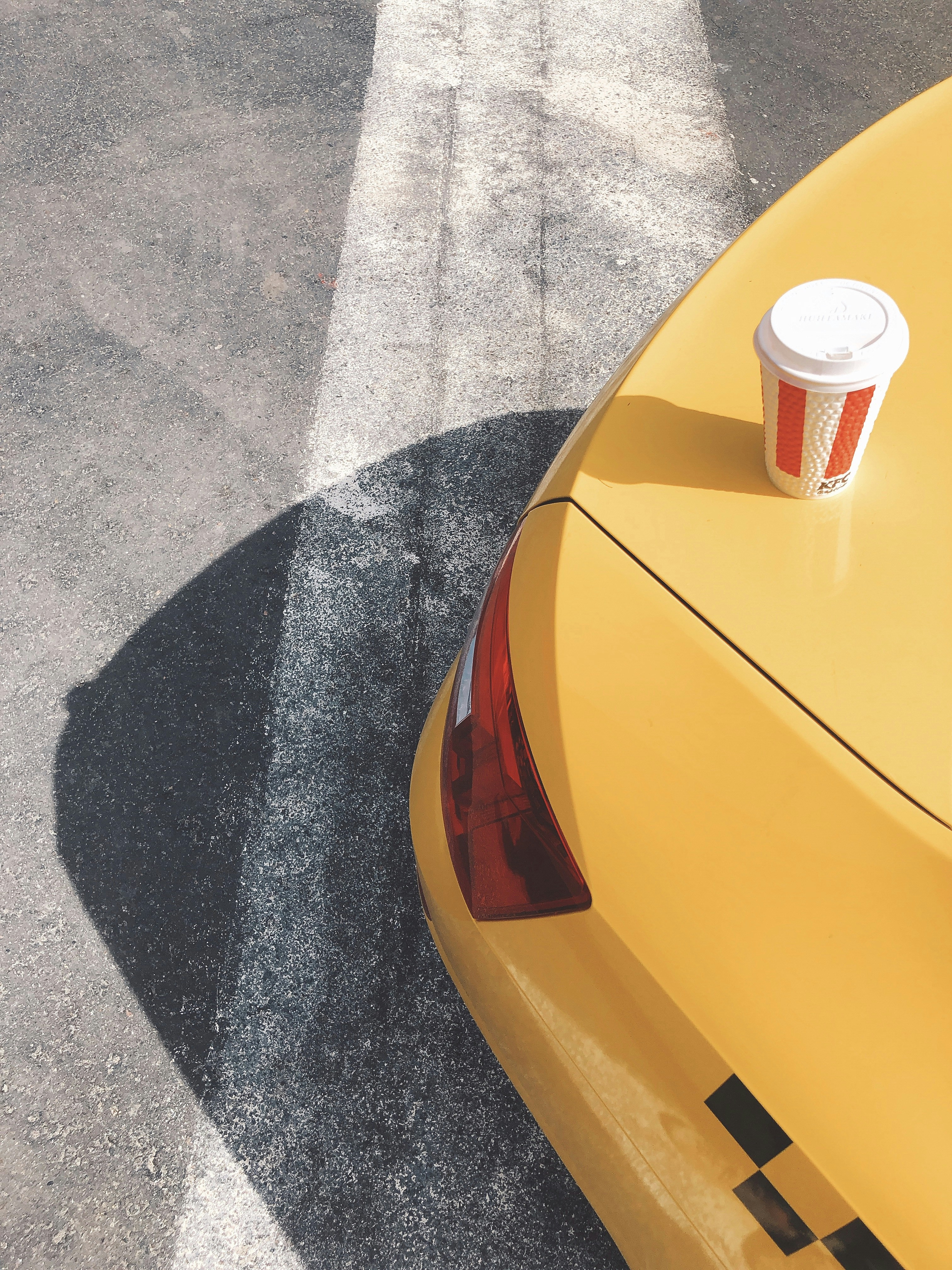 red and white disposable cup on yellow car hood