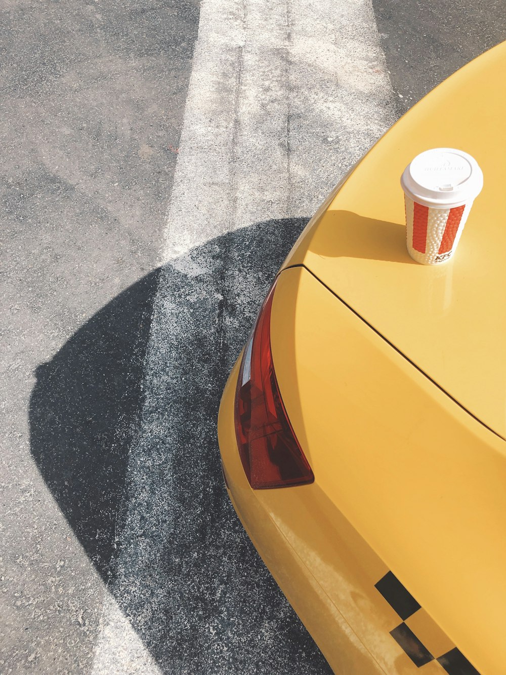 red and white disposable cup on yellow car hood