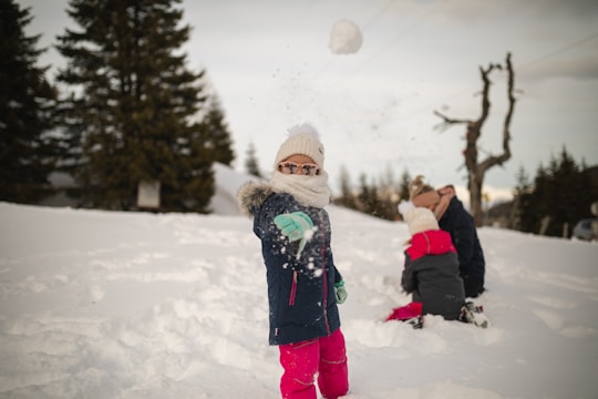 girl in pink jacket and pink pants standing on snow covered ground during daytime