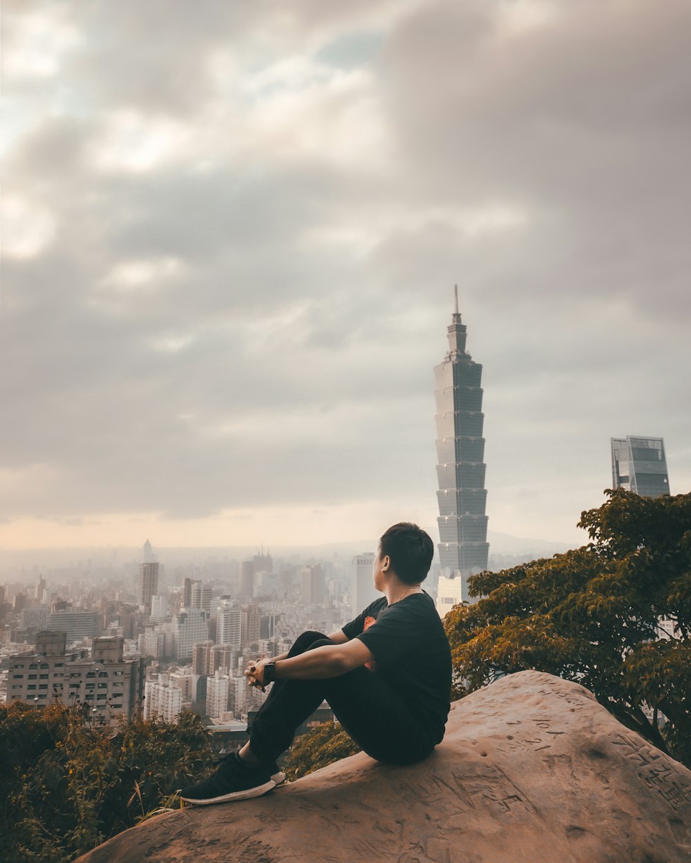 man in black jacket sitting on rock during daytime