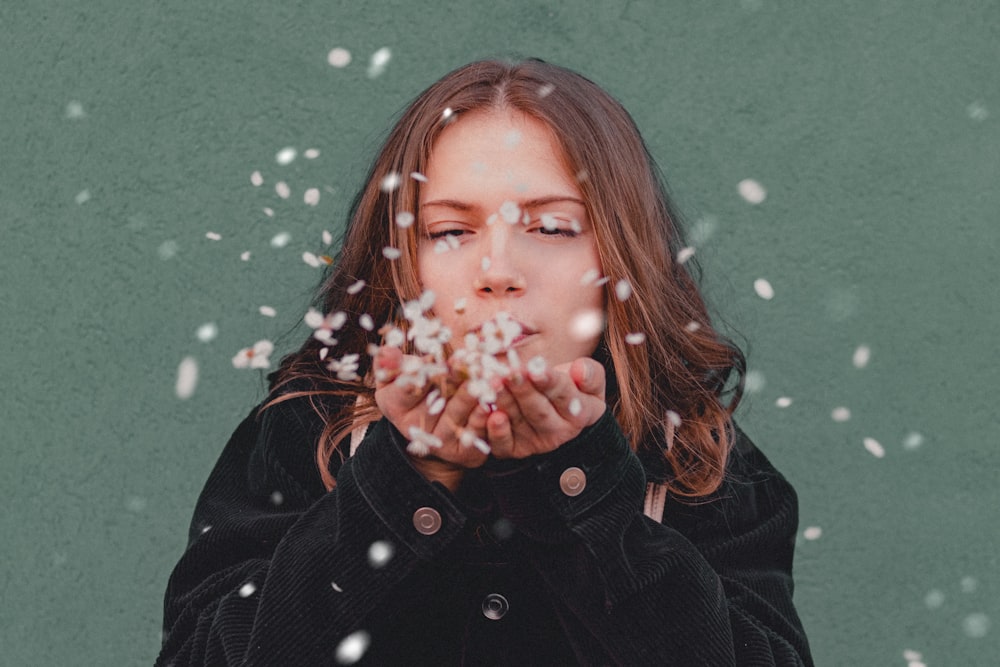 woman in black jacket holding white flower