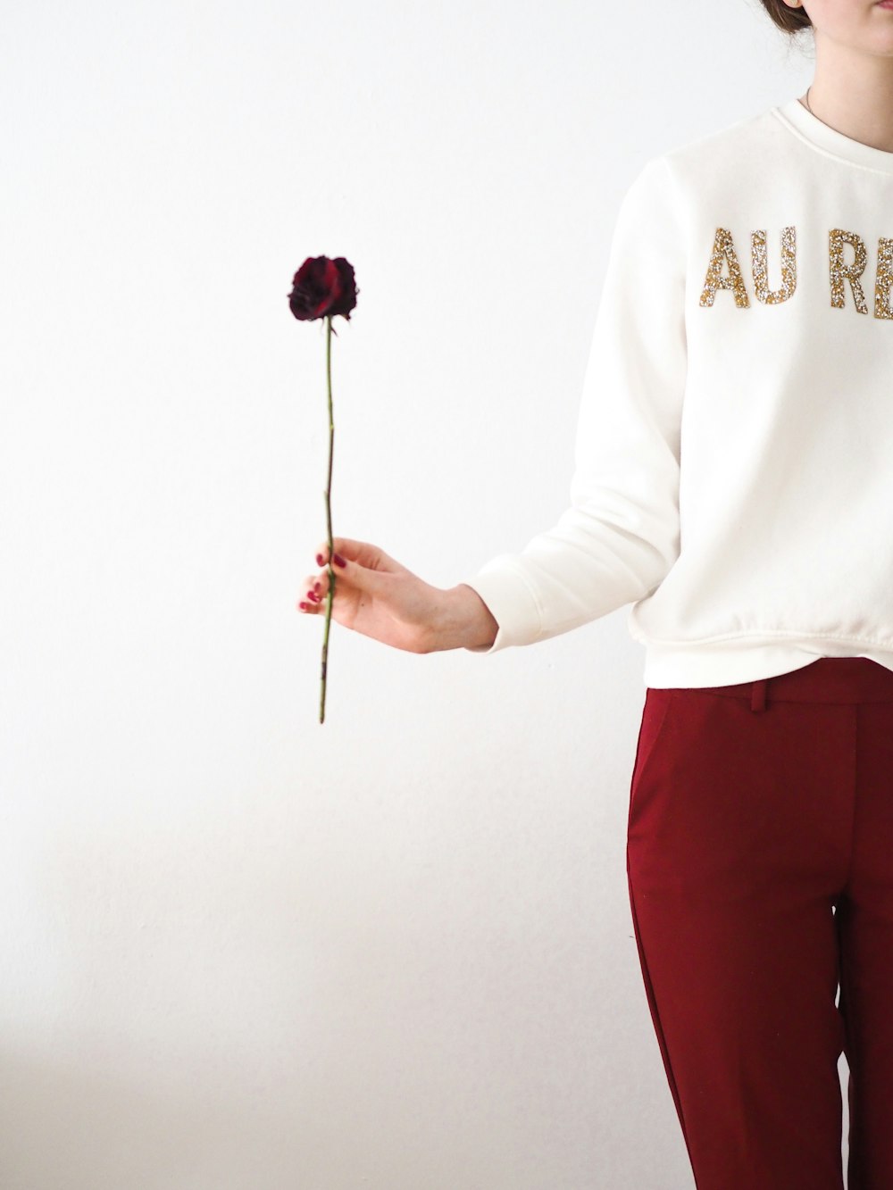 man in white sweater and red pants holding pink lollipop