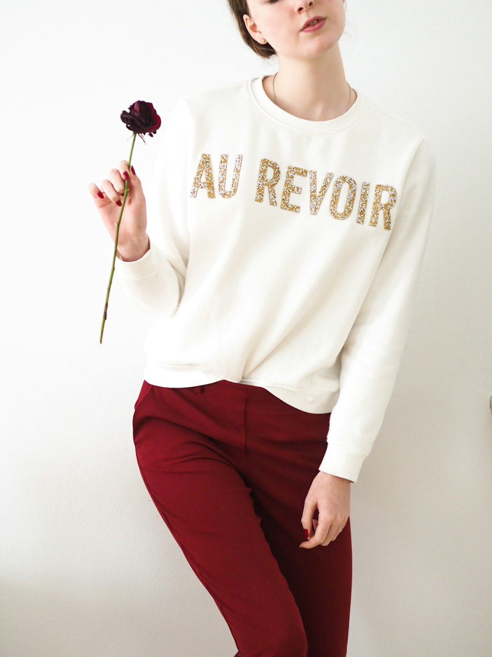 woman in white long sleeve shirt and red pants holding lollipop