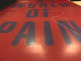 Close-up view of bold typography featuring large blue letters on a red background, with the words forming a phrase centered in the image. The surface has a reflective and glossy texture.