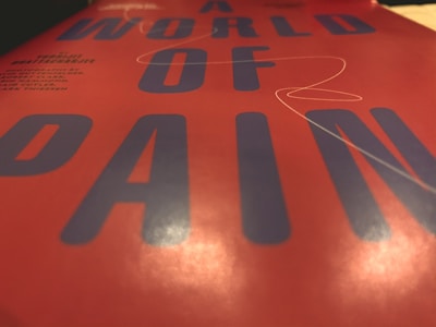 Close-up view of bold typography featuring large blue letters on a red background, with the words forming a phrase centered in the image. The surface has a reflective and glossy texture.