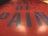 Close-up view of bold typography featuring large blue letters on a red background, with the words forming a phrase centered in the image. The surface has a reflective and glossy texture.