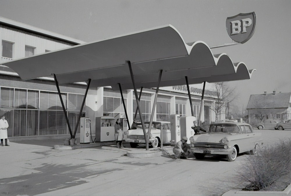 grayscale photo of cars parked near building