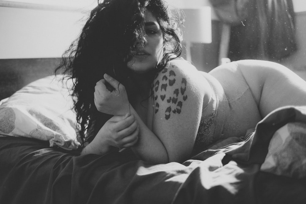 foto in scala di grigi di donna sdraiata sul letto