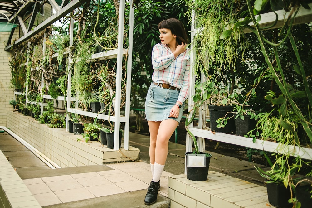 woman in white and black plaid shirt and blue denim shorts standing on white wooden bridge
