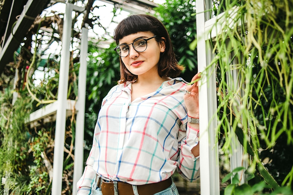 woman in white red and blue plaid dress shirt and brown pants wearing black framed eyeglasses