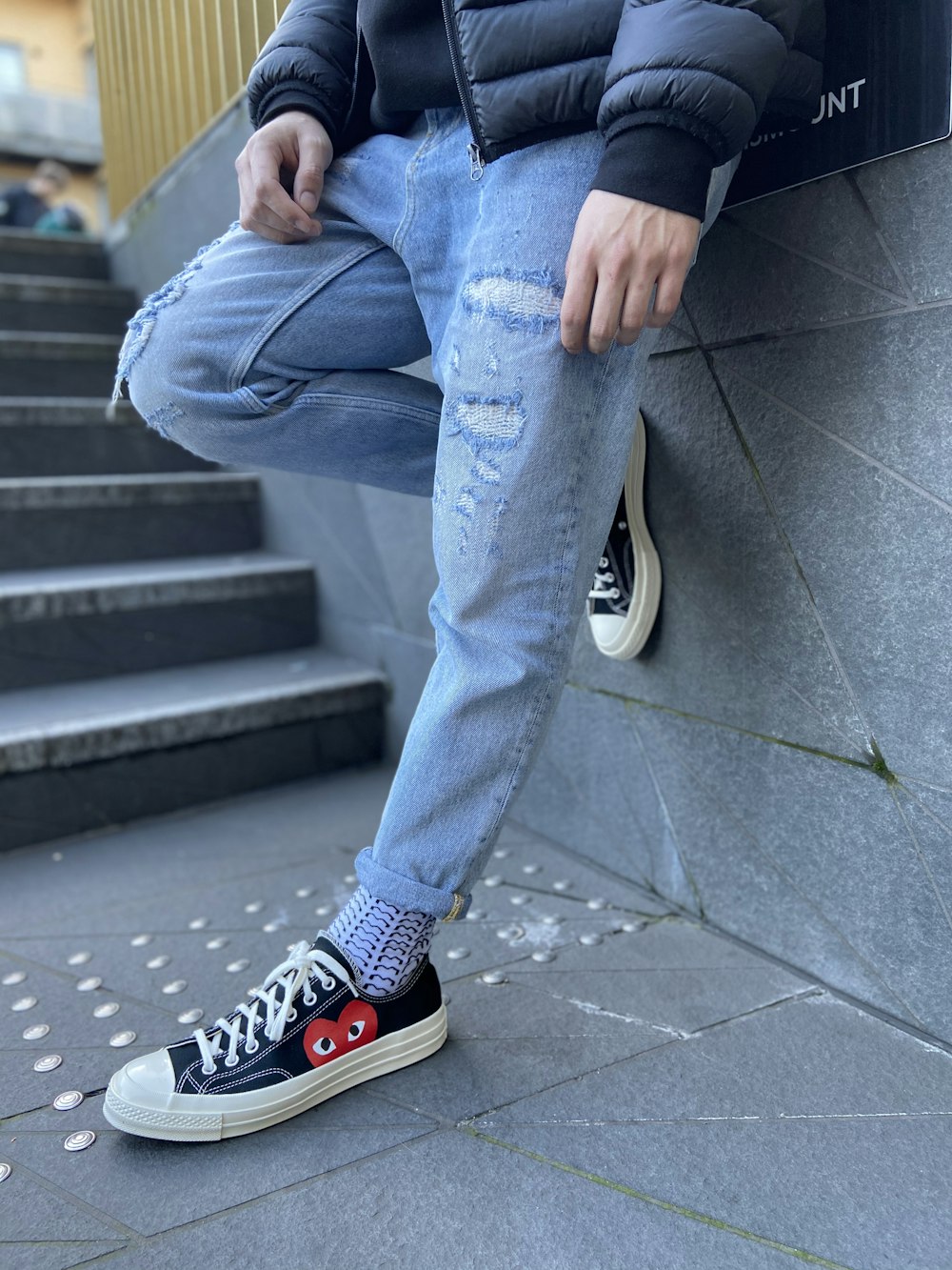 Person in blue denim jeans and black and white converse all star