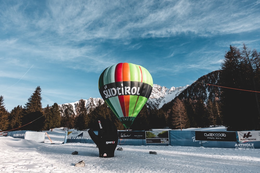 green yellow and red hot air balloon on snow covered ground during daytime