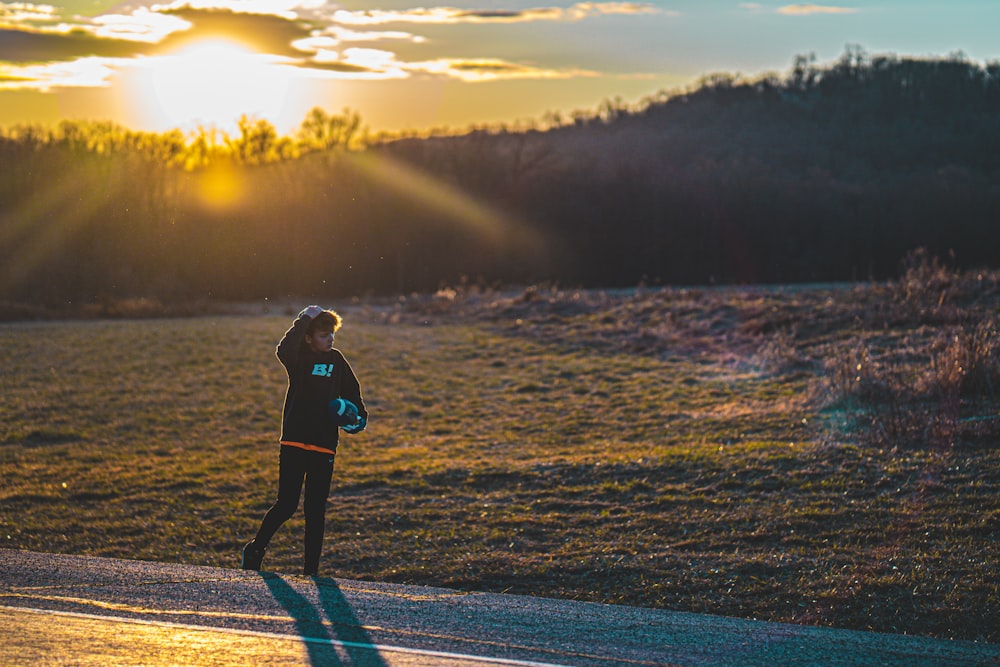 woman in black jacket walking on road during sunset