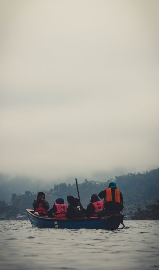 people in red and black jacket sitting on red chair during daytime in Pokhara Nepal