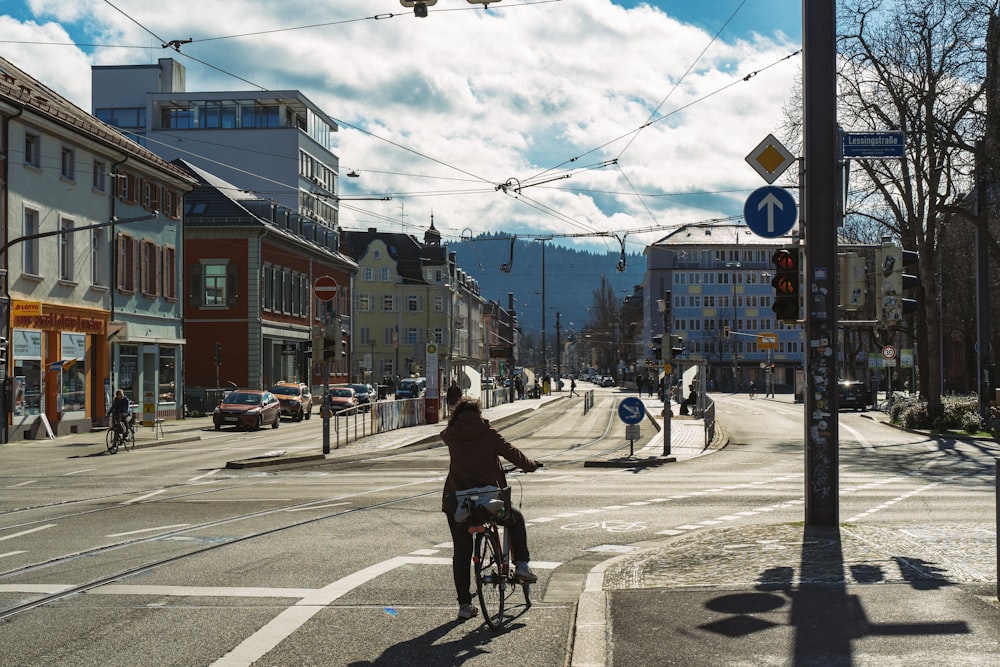 昼間、道路を自転車で走る黒いジャケットの女性