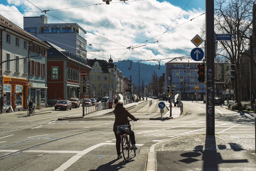 woman in black jacket riding bicycle on road during daytime