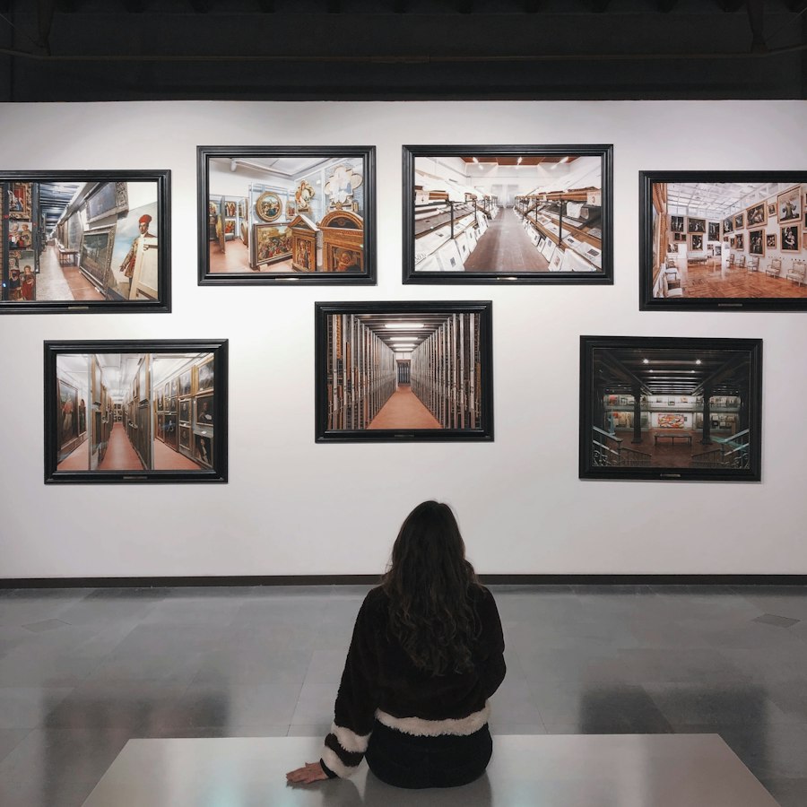 A visitor sitting in front of framed paintings in a gallery