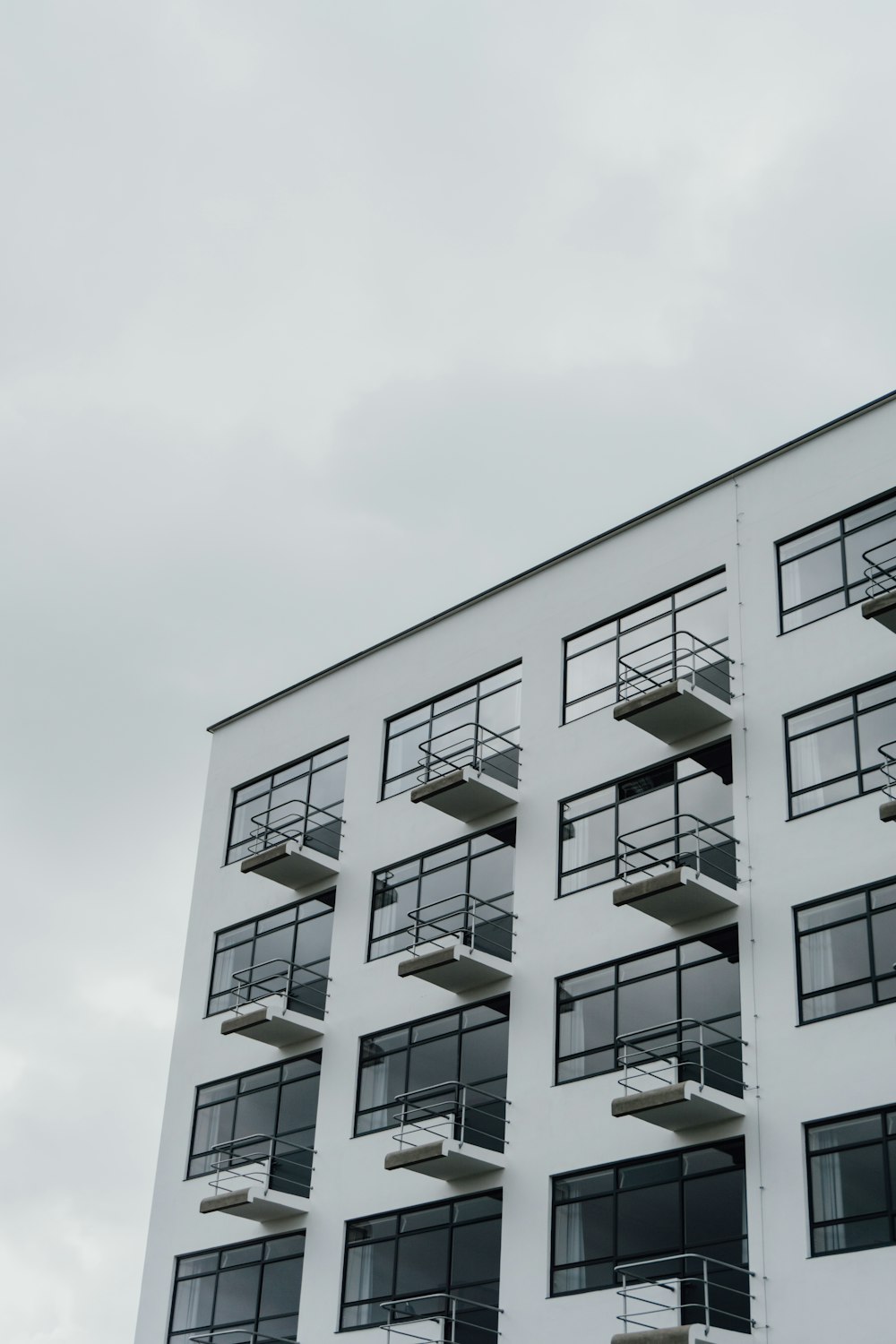 Weißes Betongebäude unter weißem Himmel tagsüber