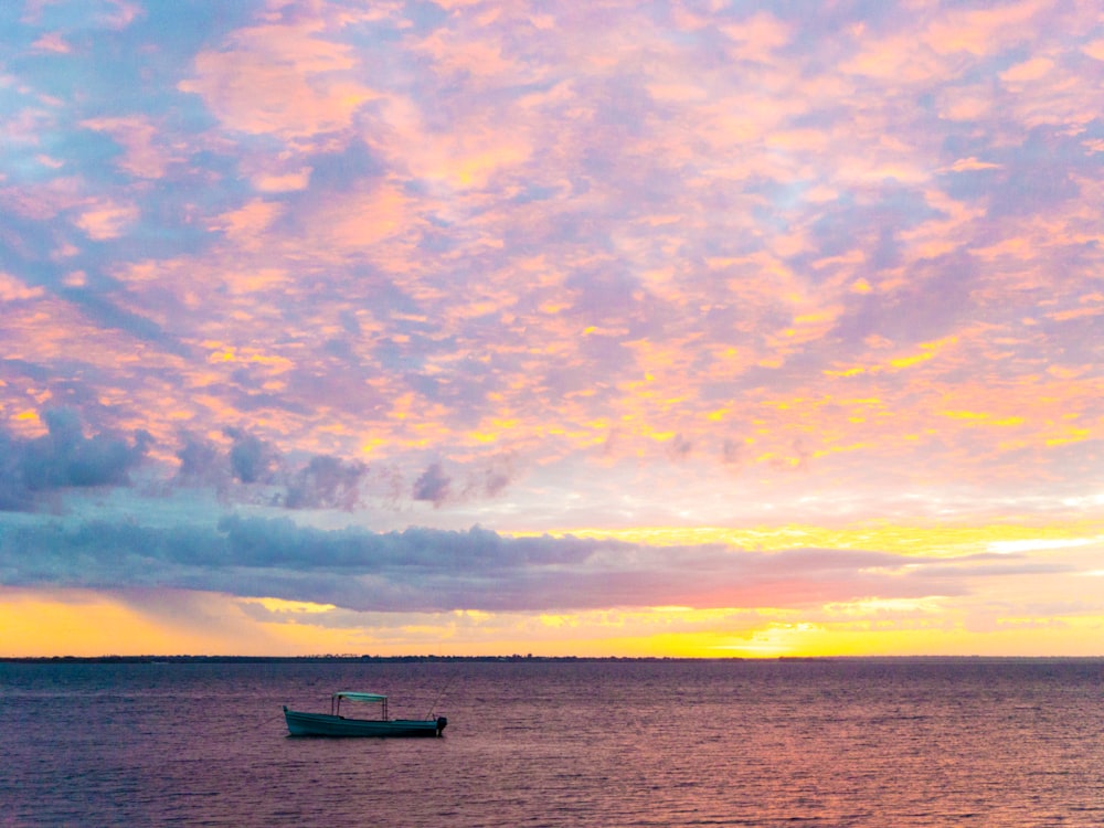 silhouette of person riding on boat on sea during sunset