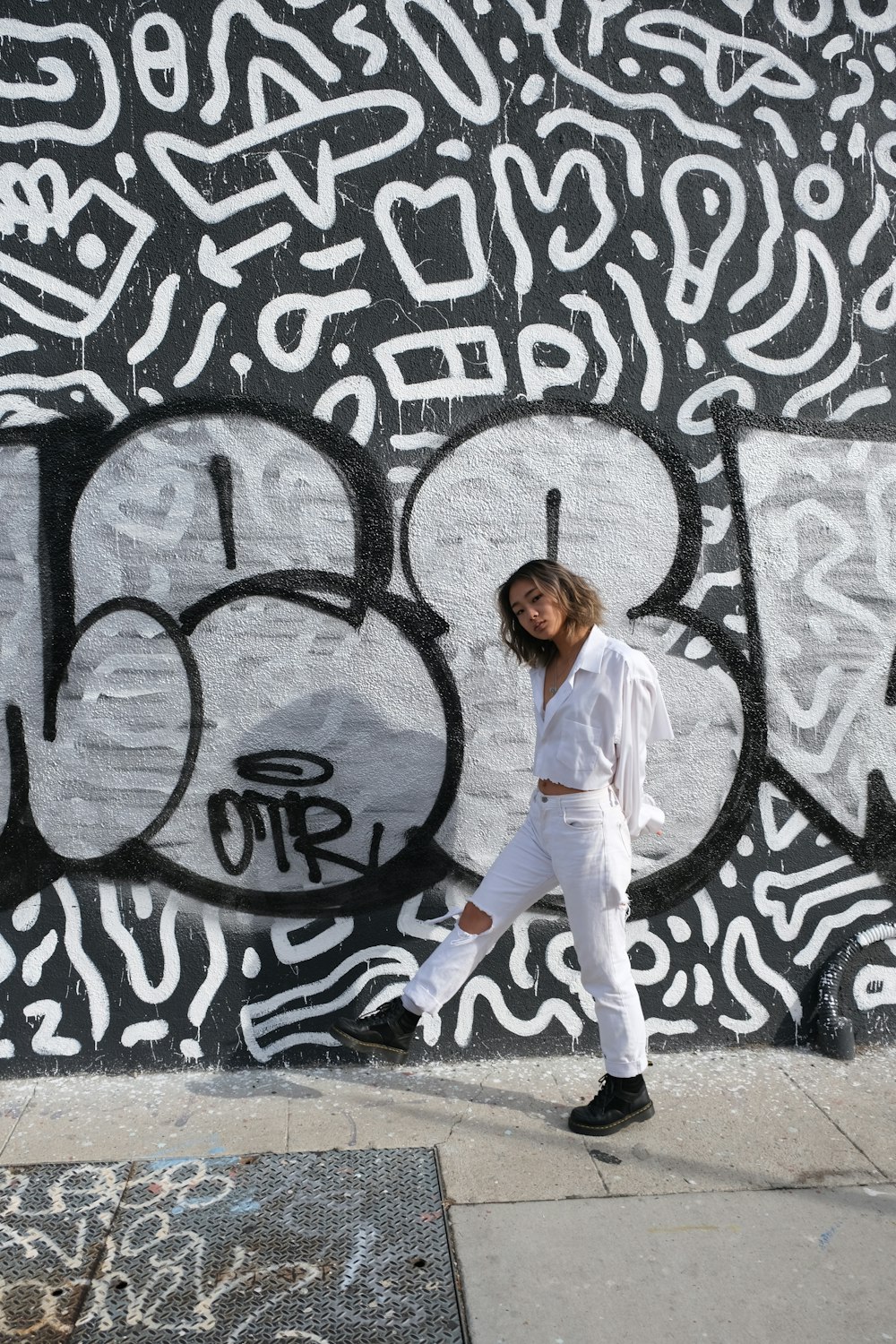 girl in white long sleeve shirt and white pants standing on gray concrete floor