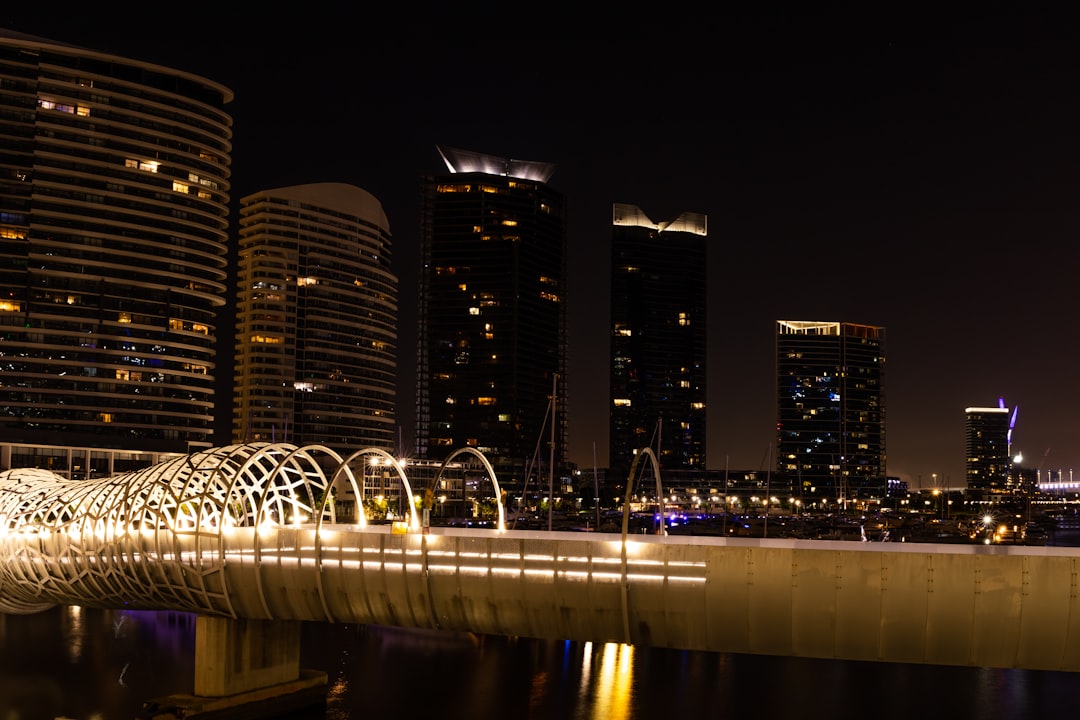 lighted bridge over body of water near high rise buildings during night time