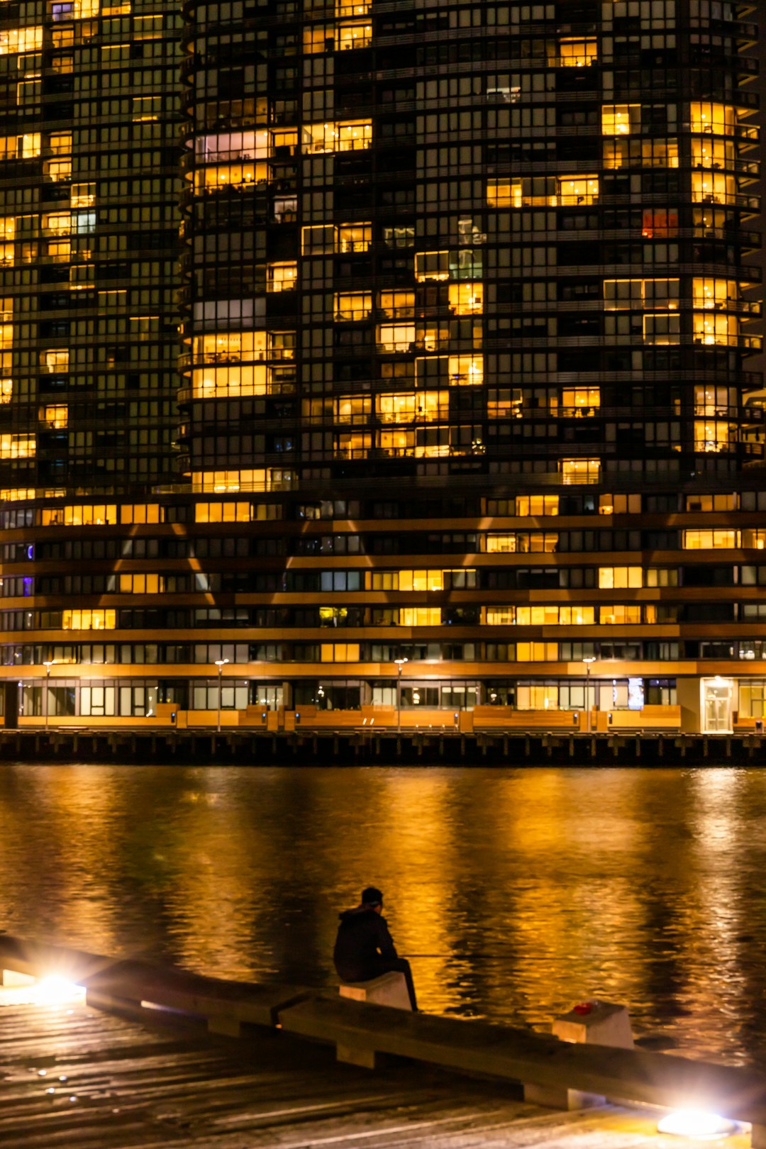 man in black jacket standing on water near building during night time