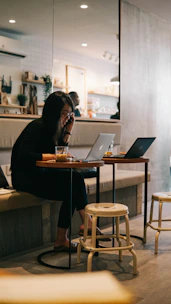 Photo of a young student happily working on a laptop in a modern Berlin café.