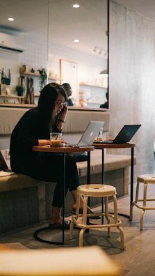 A stylish lifestyle shot of a young creative working on a laptop in a sunlit café with minimalist decor.