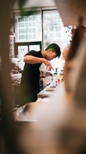 A welcoming barista gently pouring freshly brewed coffee into a ceramic cup, with soft Madini-Hijazi decor in the background.