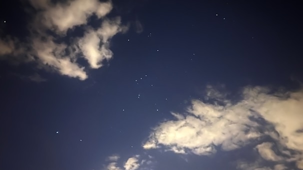 A detailed astrological chart with constellations and zodiac signs glowing softly against a dark sky background.