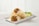 Two burritos filled with ingredients like ground meat, black beans, corn, diced peppers, and cheese are placed on a white rectangular plate. Lime wedges and cilantro garnish the display. The background is a light wooden texture.