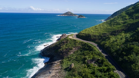 green grass covered mountain beside blue sea during daytime in Recreio dos Bandeirantes Brasil