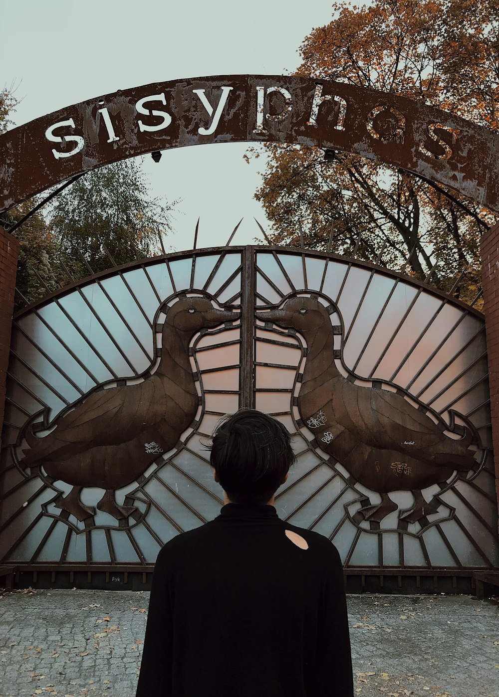 man in black shirt standing in front of brown bird wall decor