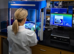 woman in white shirt standing in front of computer