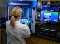 woman in white shirt standing in front of computer