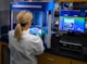 woman in white shirt standing in front of computer