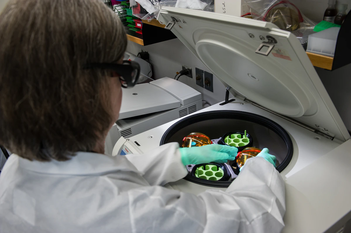 Lab technician at a centrifuge handling pharmaceutical samples